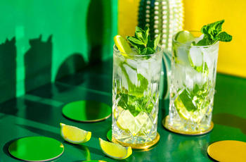 Two non-alcoholic mojitos served on a green table
