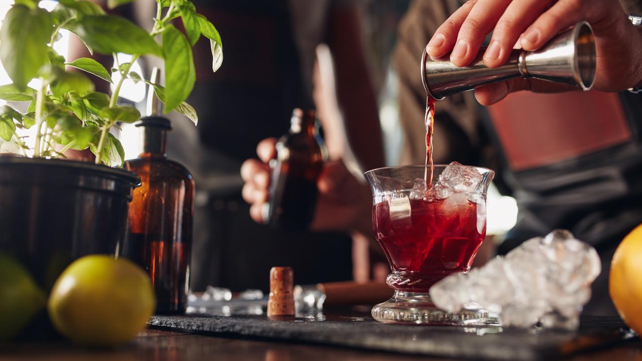 Bartender pours falernum syrup in cocktail