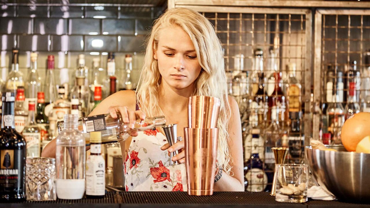 blonde beartender preparing a cocktail