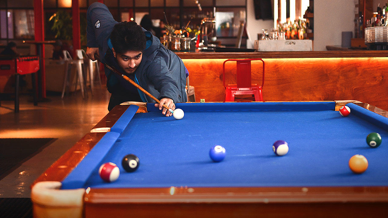 Student playing billiards during break from barman course